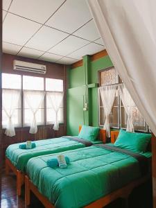 twee bedden in een kamer met groene muren en ramen bij PAI BAAN Homestay ปายบ้าน โฮมสเตย์ ถนนคนเดินปาย in Pai