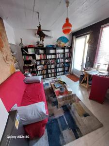 uma sala de estar com um sofá vermelho e prateleiras de livros em Demeure Prosper 1 chambre d'hôte avec petit déjeuner compris em Labégude