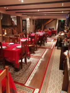 uma sala de jantar com mesas vermelhas e cadeiras de madeira em Αέσκω em Vytina
