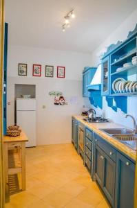 een keuken met blauwe kasten en een witte koelkast bij A Casa Romano in Ravello