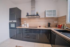 a kitchen with stainless steel appliances and wooden walls at Home - Yver - Séjour à Auxerre in Auxerre