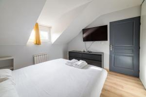 um quarto com uma cama branca e uma televisão de ecrã plano em Home - Yver - Séjour à Auxerre em Auxerre