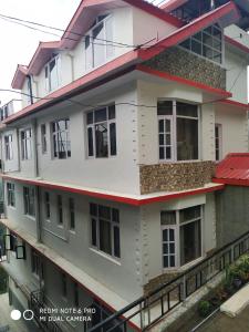 un edificio blanco con muchas ventanas en Maa Tara Anchal Cottage By BYOB Hotels en Shimla