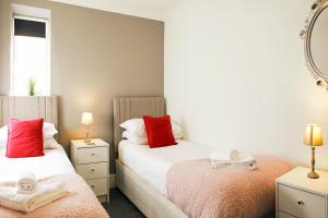 2 camas en un dormitorio pequeño con almohadas rojas en Rockpool's with outside area. en Scarborough