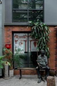 Una statua di un uomo seduto su una panchina di fronte a un edificio di BBHouse Khlongtan a Bangkok