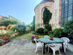 Home - Visitandines - Séjour à Auxerre في أوكسير: فناء مع طاولة وكراسي في حديقة