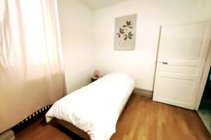 Un pequeño dormitorio con una cama blanca y una puerta en Home - Vildieu - Séjour à Coulanges, en Coulanges-la-Vineuse