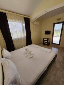 een slaapkamer met een groot wit bed met een bloem erop bij Afrodita Apartments 2 in Sinemorets