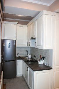 a kitchen with white cabinets and a black refrigerator at Стильная и уютная двухкомнатная квартира. in Bishkek