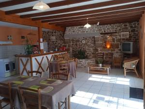 a living room with a table and a stone fireplace at Chambres d'hôtes Le Petit Angle in Saint-Broladre