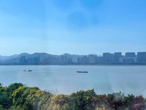 dos barcos en el agua con una ciudad en el fondo en Lexiangjia - Riverview Apartment en Hangzhou