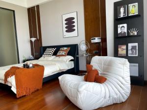 1 dormitorio con 1 cama blanca y 1 silla blanca en Lexiangjia - Riverview Apartment en Hangzhou