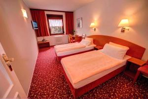 two beds in a hotel room with red carpet at Park Hotel Pruhonice in Prŭhonice