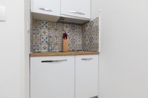 eine Küche mit weißen Schränken und einer Kachelwand in der Unterkunft Apartments with a parking space Pisak, Omis - 5975 in Pisak