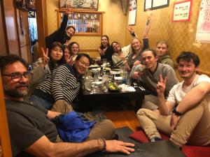 un grupo de personas sentadas alrededor de una mesa en una habitación en MAKOTO GUESTHOUSE -Enjoy your stay-, en Tokio