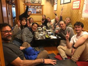 eine Gruppe von Menschen, die in einem Raum an einem Tisch sitzen in der Unterkunft MAKOTO GUESTHOUSE -Enjoy your stay- in Tokio