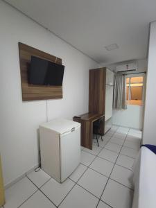 a kitchen with a refrigerator and a tv on the wall at PORTAL PARQUE HOTEL in Francisco Beltrão