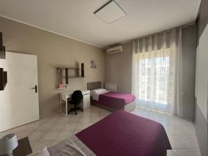 1 dormitorio con 2 camas, escritorio y ventana en Appartamento luminoso centro ladispoli, en Ladispoli