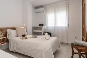 ein weißes Schlafzimmer mit einem Bett und einem Fenster in der Unterkunft tuGuest Alhamar Apartment in Granada