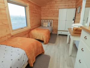 a bedroom with two beds and a desk and a window at Height End Farm Log Cabin in Bacup