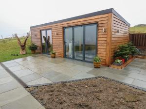 a tiny house with glass doors and a patio at Height End Farm Log Cabin in Bacup