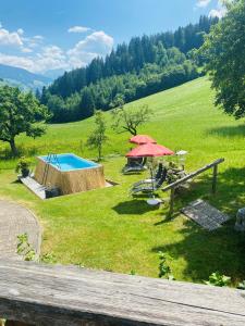 een resort met een zwembad en parasols in een veld bij Wöscherhof in Kaltenbach