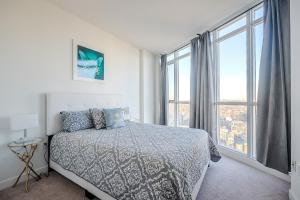 a white bedroom with a bed and a large window at GLOBALSTAY. Elegant Downtown Apartments in Toronto