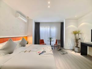 a bedroom with a large white bed and a desk at Nan'er Jieli Hotel - Chengdu Tianfu International Airport Branch in Jianyang