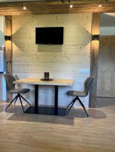 einen Holztisch mit zwei Stühlen und einen TV an der Wand in der Unterkunft Wöscherhof in Kaltenbach
