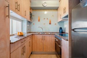 a kitchen with wooden cabinets and a stainless steel refrigerator at Alea Rentals - Bell Racó in La Pineda