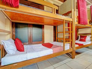 2 Etagenbetten mit roten und weißen Kissen in einem Zimmer in der Unterkunft OYO 92851 Homestay Borobudur Specpacker Syariah in Yogyakarta