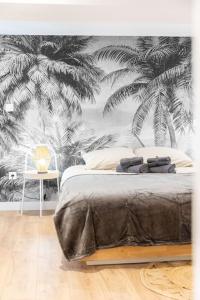 um quarto com uma cama com um mural de palmeiras em Jungle Room de Charme em Marselha