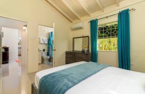 a bedroom with a bed and a bathroom with a window at Drax Hall Country Club in Mammee Bay