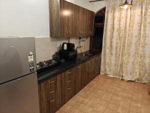 een kleine keuken met houten kasten en een koelkast bij Nakul's Nook in Varca in Varca