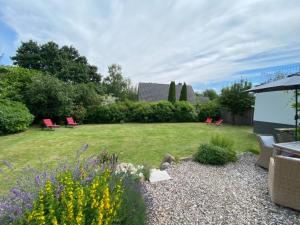 a garden with red chairs and a field of grass at StrandGlück in Kleinwaabs
