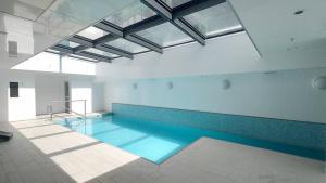 a swimming pool with blue water in a building at Sky Stars Park Apartment in Auckland
