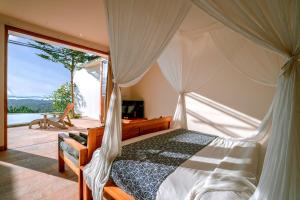a bedroom with a canopy bed and a balcony at Sumberkima Resort in Pemuteran