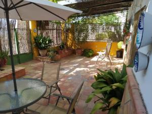 een patio met een tafel en stoelen en een parasol bij Alojamiento Rural Huerto del Francés Dormitorios y baños disponibles según nº de huéspedes in Pegalajar