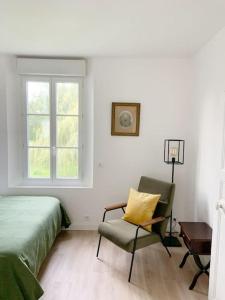 a bedroom with a bed and a chair and a window at Country House - Garden - Private access to the Loir in La Chartre-sur-le-Loir