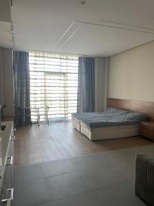 um quarto com uma cama, uma mesa e uma janela em Sea Breeze Apartments Lighthouse em Baku