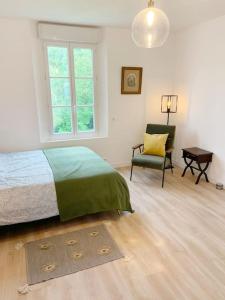 a bedroom with a bed and a chair and a window at Country House - Garden - Private access to the Loir in La Chartre-sur-le-Loir