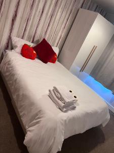 倫敦的住宿－Lovely en-suite double room，一张带红色枕头的白色床和毛巾