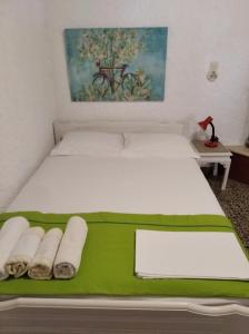 a bed with a green blanket and towels on it at Ioanna's house #dialiskari1# in Limnionas