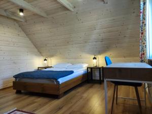 two beds in a room with wooden walls and wooden floors at Kraina Biebrzy - domki nad Biebrzą in Wroceń