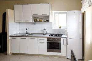 La cuisine est équipée de placards blancs et d'un réfrigérateur blanc. dans l'établissement Apartment Old Town - Bambo, à Knin