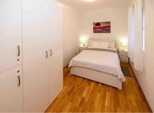 Apartment Old Town - Bambo في كنين: غرفة نوم بسرير ابيض و دواليب بيضاء