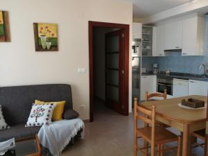 a kitchen and a living room with a table and a couch at Apartamentos Colmado in Sanxenxo