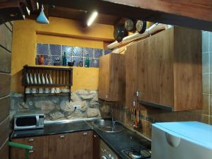 een keuken met houten kasten en een wastafel bij Alojamiento Rural Huerto del Francés Dormitorios y baños disponibles según nº de huéspedes in Pegalajar