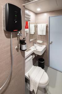 a bathroom with a toilet and a tv on the wall at BRIX KLIA By Pinetree in Sepang