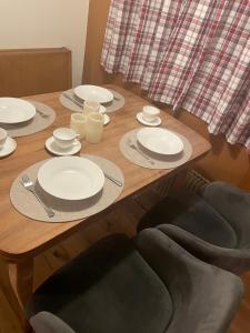 una mesa de madera con platos y utensilios blancos. en Studio Chalet Sunnehöckli en Hasliberg